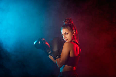 Caucasian woman boxing with colored gels and smoke.の写真素材