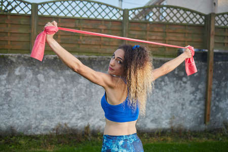 Caucasian blonde woman performing stretches with elastic tapes, lifestyle concept, fitness.