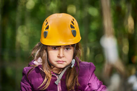 portrait of a 5-year-old girl having fun with a safety helmet in a forestの写真素材