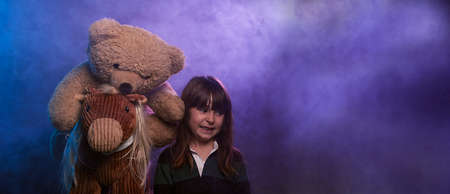 panoramic portrait with copy space of a child and her toys having fun with smoke and colored lights.