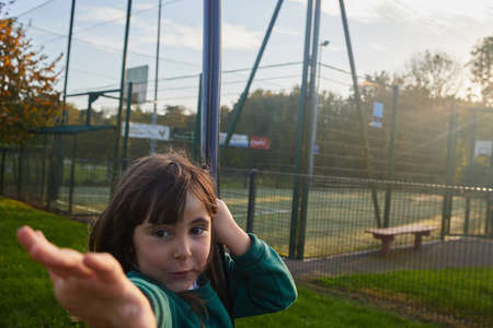 young girl playing hanging on a rope and with her hand near the camera with copy space.