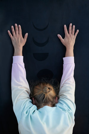 woman in her forties performing a yoga stretch on a mat with no recognizable faceの写真素材