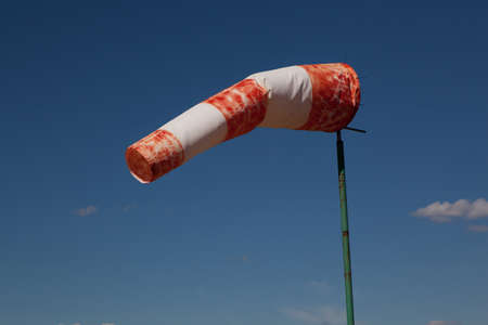 red wind vane against a blue cloudy skyの写真素材