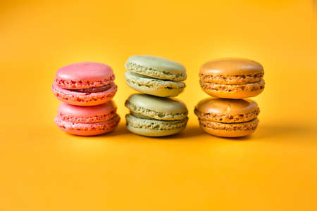 pink, orange and green macarons on yellow backgroundの写真素材