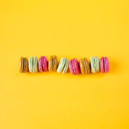pink, brown, orange and green macarons on yellow backgroundの写真素材