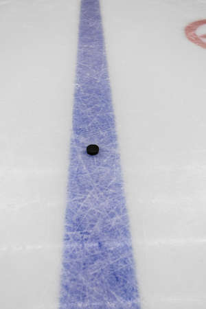 detail blue line with puck on ice hockey rink