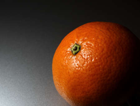 Orange slightly illuminated, taken on the silver background and with limited lightの写真素材