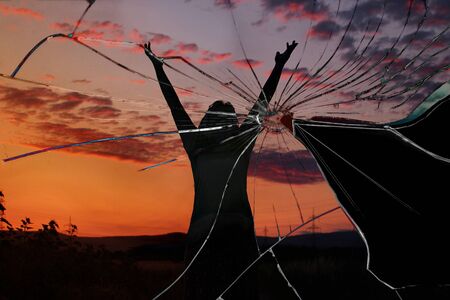 cracked image, a woman in the sunset light raised her hands up, concept of a failed vacation, canceled trip, spoiled vacation, disaster, quarantine, isolationの写真素材