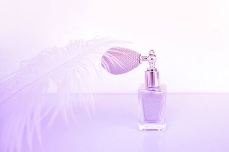 body schimmer dust in vintage bulb spray bottle on purple background. crystal beauty dust. Softly shimmering glitter powder in a retro design bottle, natural makeup conceptの写真素材