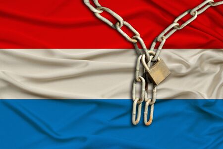 iron chain and lock on the silk national flag of Luxembourg with beautiful folds, the concept of a ban on tourism, political repression, crime, violation of the rights and freedoms of citizensの写真素材