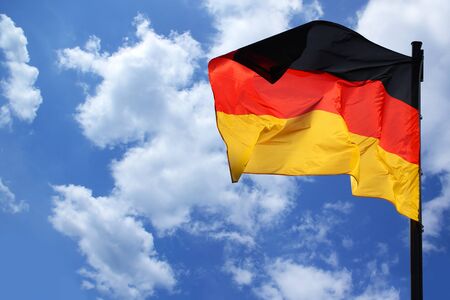 flag of the federal republic of Germany freely flutters in the wind against a blue sky, , concept of tourism, economy, politics, emigration, businessの写真素材