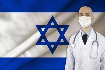 male doctor with a stethoscope on the background of the israel national silk flag, concept of national medical care, health, insurance, tourismの写真素材