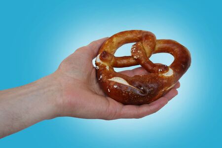 beautiful freshly baked pretzel, German national dish with a golden brown crust in a male hand...