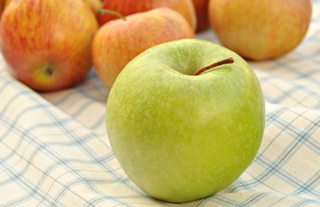 Green apple in the foreground, with several red apples at the bottomの写真素材