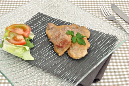 Fillets of pork with salad on a black rectangular plateの写真素材