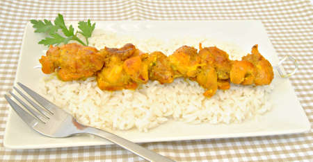 Skewer of chicken on a bed of rice decorated with parsley leafの写真素材