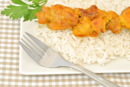 Skewer of chicken on a bed of rice decorated with parsley leafの写真素材