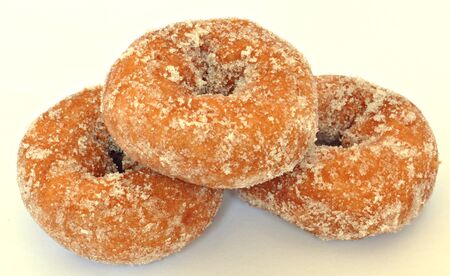 Three donuts with sugar, surrounded by white backgroundの写真素材