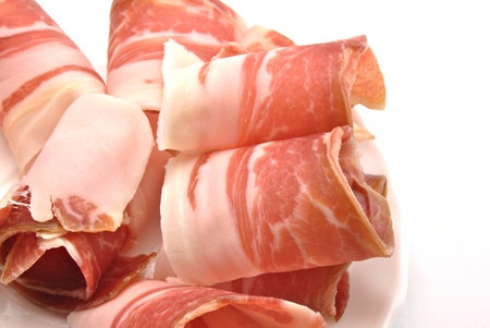 Serrano ham slices next to each other, surrounded by white backgroundの写真素材