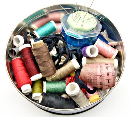 Utensils sewing with colored threads, needles, tape measure and a thimble in a boxの写真素材