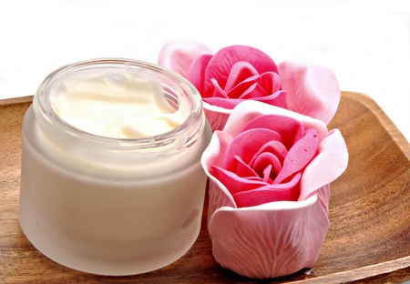Cream jar with two roses on wood