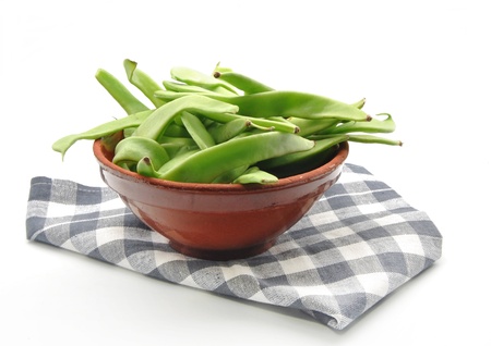 Several green beans in a bowl, on a napkin