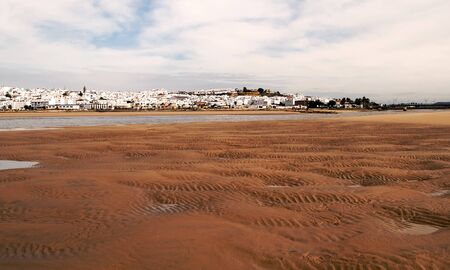 White village of Conil de la Frontera located in the Spanish province of Cadiz we see it from the beach on a cloudy dayの写真素材