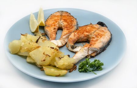 Sliced grilled salmon with fries served on a plateの写真素材