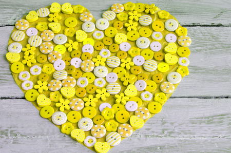 Yellow heart covered with colorful buttons.Valentine's day. From aboveの写真素材