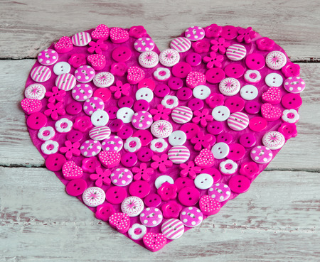 Pink heart covered with colorful buttons.Valentine's day. From aboveの写真素材