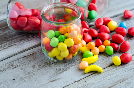 Close-up of multicolored sweets and caramels on table and in glass jarの写真素材