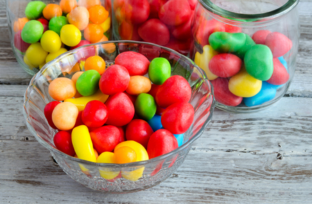 Close-up of colorful bright sweets in glass bowls on wooden tableの写真素材