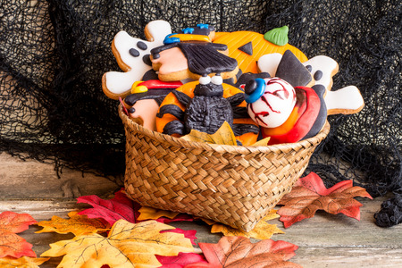 Wattled basket full of halloween homemade cookies on autumnal foliageの写真素材