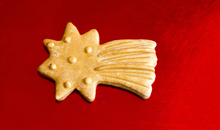 Close-up of gold Christmas star cookie on red metal backgroundの写真素材