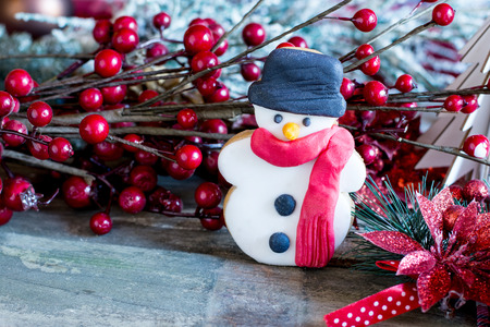 Close-up of butter cookie in shape of snowman against of berry branch on tableの写真素材