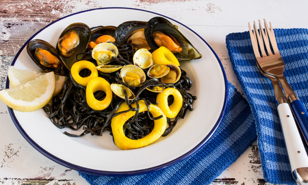 Close up of plate of salad with seaweed and calamary sliced rings and oisters served with slice of lemonの写真素材