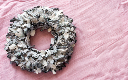 Top view of creative silver Christmas wreath on pink tablecloth in daylightの写真素材