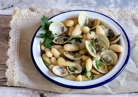 Close-up of delicious boiled soup with mussels, parsley and baked gnocchi in plate with blue rim on napkinの写真素材
