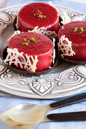 Close-up of pink jellied berries in round shape on plate with pistachio on topの写真素材