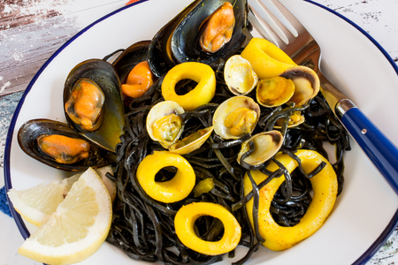 Close up of plate of salad with seaweed and calamary sliced rings and oisters served with slice of lemonの写真素材