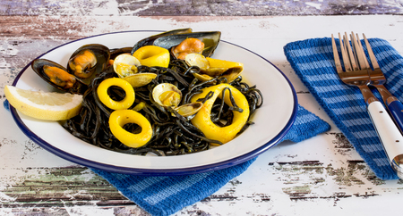 Close up of plate of salad with seaweed and calamary sliced rings and oisters served with slice of lemonの写真素材