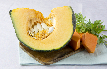 Raw pumpkin cut into pieces on a boardの写真素材