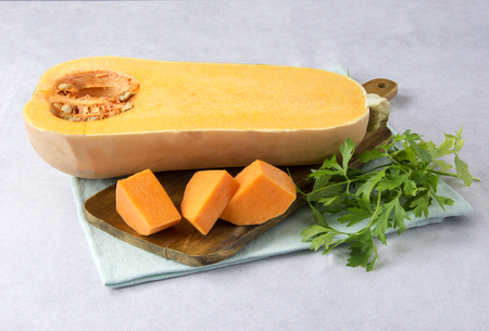 Raw pumpkin cut into pieces on a boardの写真素材