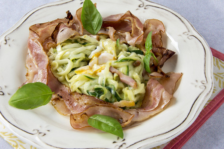 Scrambled eggs with zucchini, carbonara sauce and baconの写真素材