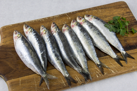 Several fresh sardines on a wooden boardの写真素材