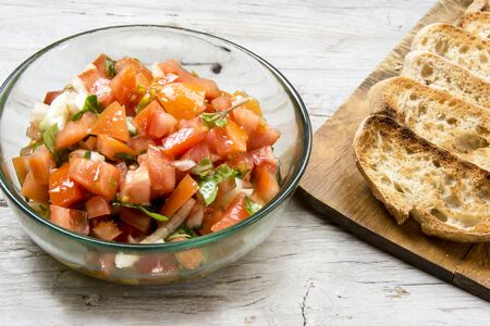 Ingredients to make bruschetta, typical Italian appetizer with tomato, basil and toastの写真素材