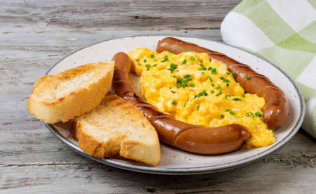 Scrambled eggs with sausages served on a plateの写真素材
