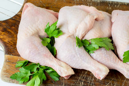 Raw chicken thighs on a wooden boardの写真素材