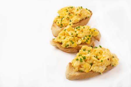 Scrambled eggs served on bread toast on white backgroundの写真素材