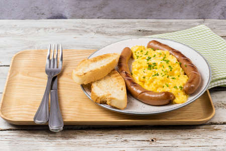 Scrambled eggs with sausages served on a plateの写真素材
